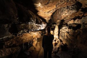 A woman is shown from behind during a lantern tour of a cave