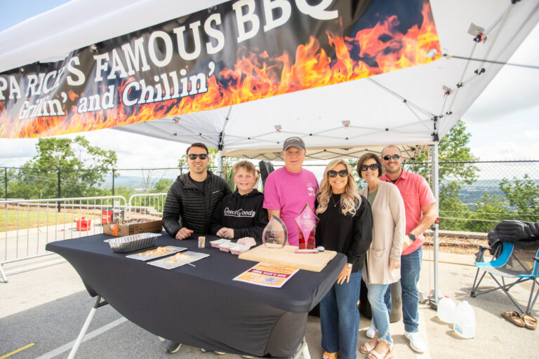 A small group of men and women gather under on awning at Battle Below the Clouds BBQ competition.