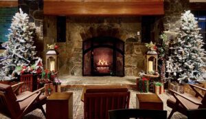 A fire burns in a stone fireplace at Ruby Falls' historic castle with Christmas trees on each side featuring woodland decorations and candle lights