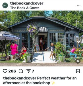 Photo of a small one-story home that has been turned into a local bookshop. Customers are sitting at tables in front of the shop drinking coffee and enjoying the a spring day. 
