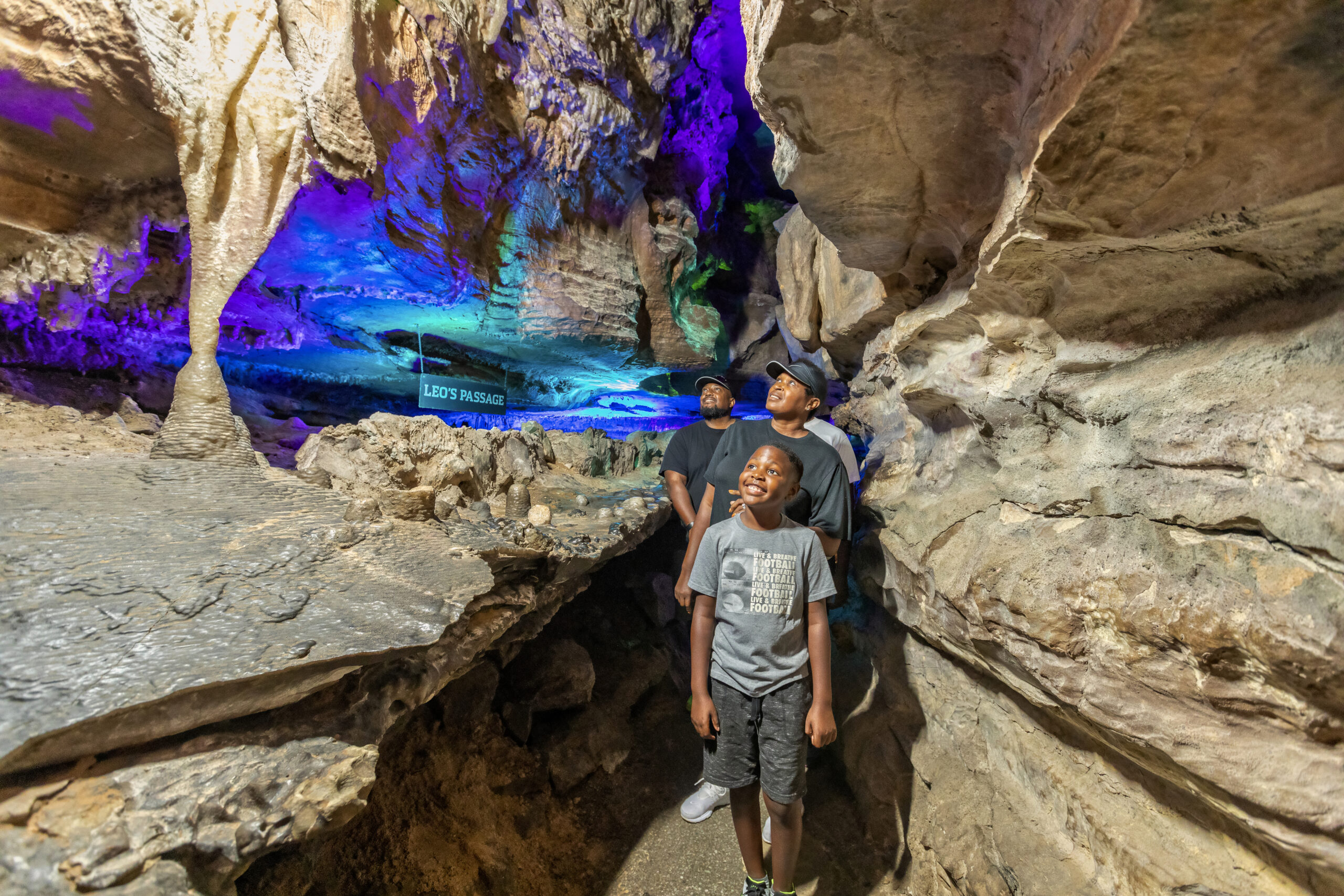 A family walks admiring the caves next to a sign reading Leo's Passage