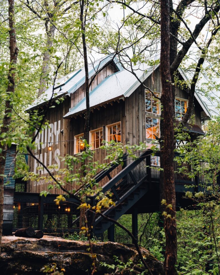 A treehouse in the woods featuring the words Ruby Falls painted on the outside wall of the treehouse.