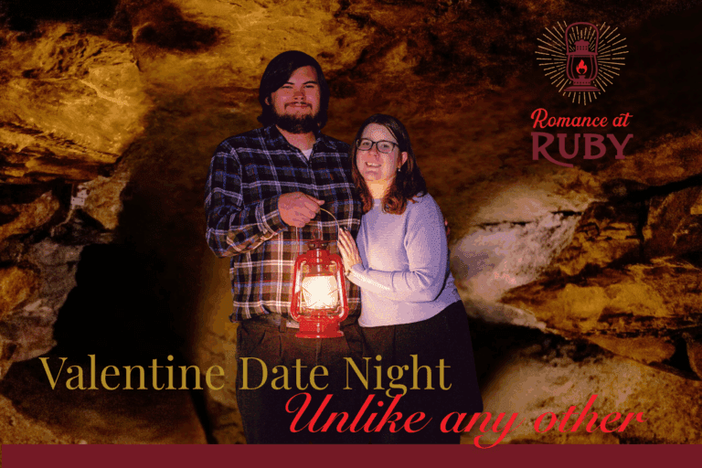 A man and woman stand side by side inside a cave. The man has one arm around the woman and his other hand is holding a red lantern in front of his body.